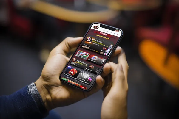 Um homem concentrado em seu laptop com estatísticas ao vivo ao fundo, destacando os recursos dedicados de esportes e jogos do app móvel 29P.